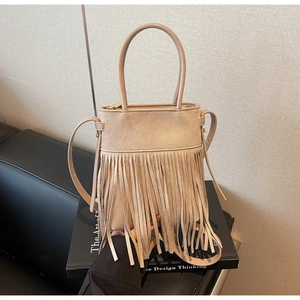 Détail du sac seau bohème en daim beige avec de longues franges et une bandoulière en cuir