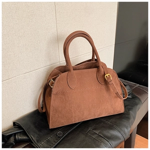 Dettaglio borsa tote in pelle scamosciata marrone con fibbie dorate e tracolla regolabile