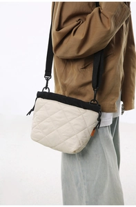 Quilted beige nylon bucket bag detail showing black drawstring closure and orange brand tag