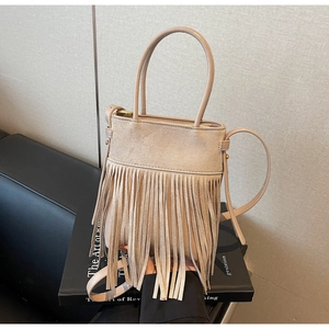Vue détaillée du sac seau à franges beige avec texture suédée sur cuir noir élégant