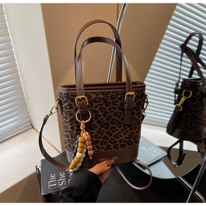 Detail of leopard print bucket bag with leather handles and colorful beaded tassel charm