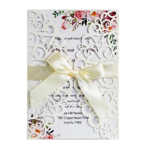 Macro detail of laser-cut lace wedding invitation with cream envelope and silk ribbon