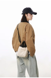 Detail view of quilted cream bucket bag featuring black drawstring and shoulder strap