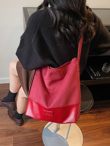Red suede tote bag with large capacity for commuting shown on a shoulder in warm light