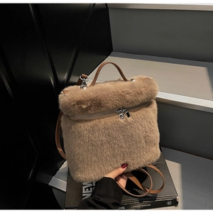 Detail showing plush camel faux fur texture and brown leather handle of the handbag