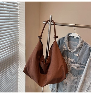 Detail of large dark brown tote bag with soft pleated fabric and shoulder strap orb detail