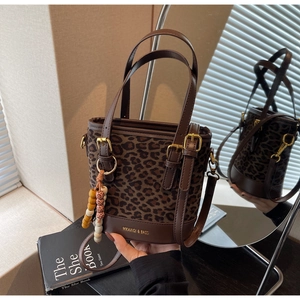 Detail of leopard print bucket bag with brown leather base and beaded charm accessory