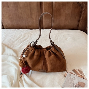 Détail du sac seau en daim marron avec pompon et perles en bois décoratives