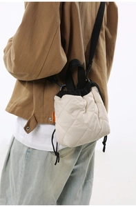 Quilted beige nylon bucket bag with drawstring closure shown on shoulder of a model