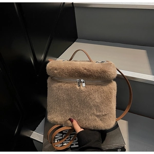 Detail of plush brown faux fur backpack featuring silver zippers and leather handle