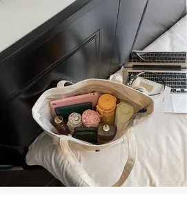 Détail d'un grand cabas en toile ivoire montrant un intérieur spacieux pour tablettes