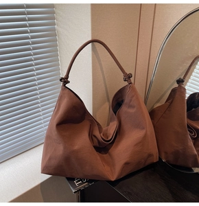 Detail of a large brown minimalist tote bag with unique knotted strap and dark bead accents