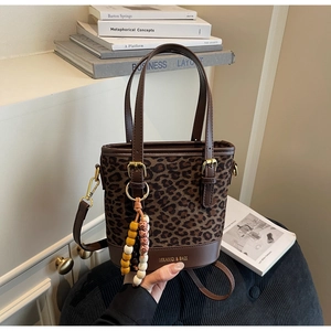 Detailed close-up of leopard print bucket bag with leather handles and gold metal accents