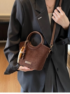 Deep brown matte suede bucket bag with round handles and colorful wooden bead pendant