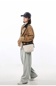 Detail of cream quilted bucket bag with black trim and nylon strap worn by a model
