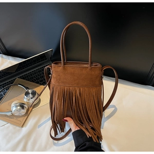 Détail d'un sac seau vintage en daim marron avec de longues franges et des poignées