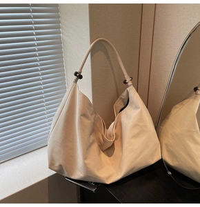 Detail of minimalist beige suede tote featuring wooden beads and soft pleated texture