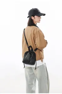Quilted black nylon bucket bag worn crossbody style over a casual jacket and jeans