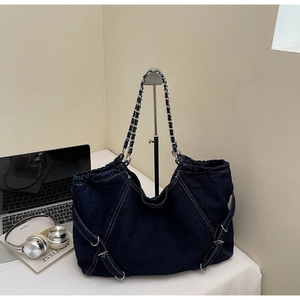 Detail of dark blue denim tote bag with silver chain strap and drawstring closure