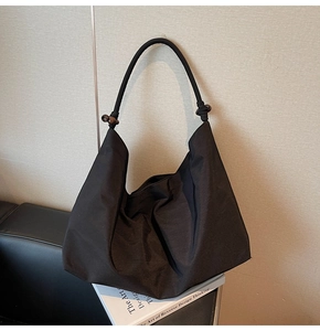 Detail of black suede hobo bag featuring woven rope strap and decorative wood beads