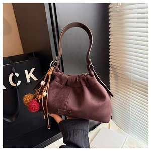 Détail du sac seau en daim bordeaux avec plis nuage et pompon décoratif en perles colorées