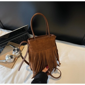 Détail du sac seau à franges marron vintage avec texture suédine en scène quotidienne