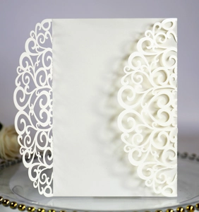 Detail of laser-cut lace pattern on ivory wedding invitation cover with pearlescent finish
