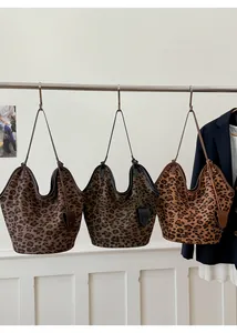 Trois variantes de sacs fourre-tout en daim à imprimé léopard sur un support d'exposition