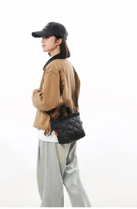 Detailed side view of black quilted nylon bucket bag on model with casual street style