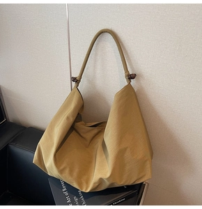 Detail view of mustard yellow suede tote bag featuring brown wooden bead accents on strap