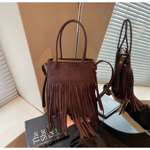 Détail d'un sac seau vintage en daim marron avec de longues franges et une poignée chic