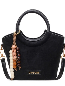 Minimalist black matte bucket bag with round handles and colorful beaded charm