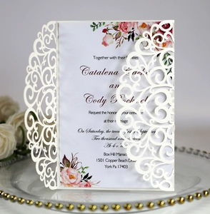 Detail of laser-cut lace wedding invitation with pink floral inner card on glass tray