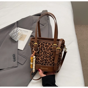 Detailed shot of leopard print bucket bag with brown trim and decorative beaded charm
