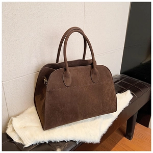 Primo piano di una borsa tote vintage in pelle scamosciata marrone scuro con manici