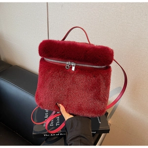Detailed close-up of dark red plush backpack with silver metal zipper and leather strap