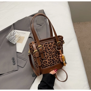 Detail of leopard print canvas bucket bag with brown leather strap and wooden bead charm