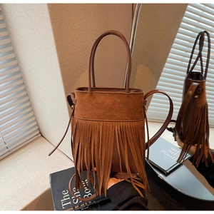 Détail du sac seau vintage en daim marron avec de longues franges et anse en cuir