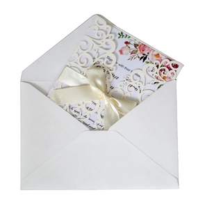 Detail of laser-cut lace wedding invitation with floral inner card and silk ribbon bow