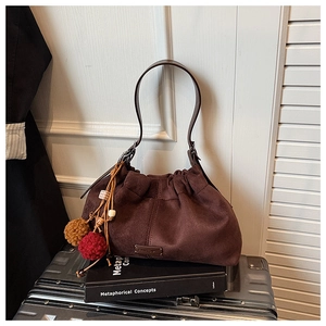 Détail du sac seau en daim marron foncé avec plis nuage et breloque boule de fourrure