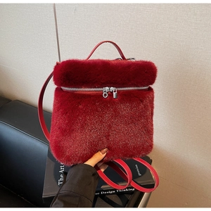 Close-up of fluffy red faux fur mini backpack with silver metal zippers and leather handle