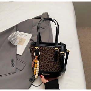 Close-up of leopard print bucket bag with beaded charm and black leather details