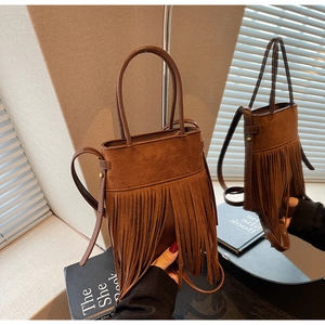 Détail du sac seau marron vintage avec longues franges et reflet dans le miroir