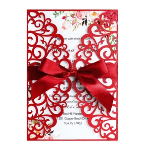 Detail of red laser cut lace wedding invitation with a satin ribbon and floral card