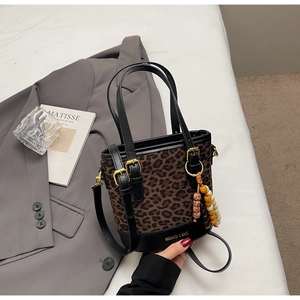 Detail of leopard print bucket bag with leather handles and colorful beaded charm decoration