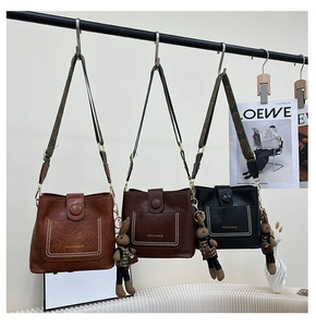 Detail of vintage bucket bags in three colors featuring wide woven straps and rabbit charms