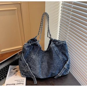 Detail of vintage blue denim tote bag with side buckles and woven metal chain strap