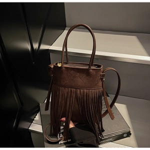 Gros plan d'un sac seau vintage en daim marron foncé avec des franges et une fermeture dorée