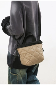 Detail of khaki quilted bucket bag featuring black trim and adjustable shoulder strap