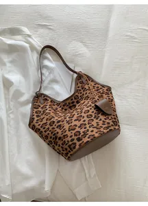 Détail du sac cabas léopard en simili daim avec des anses en cuir marron sur tissu